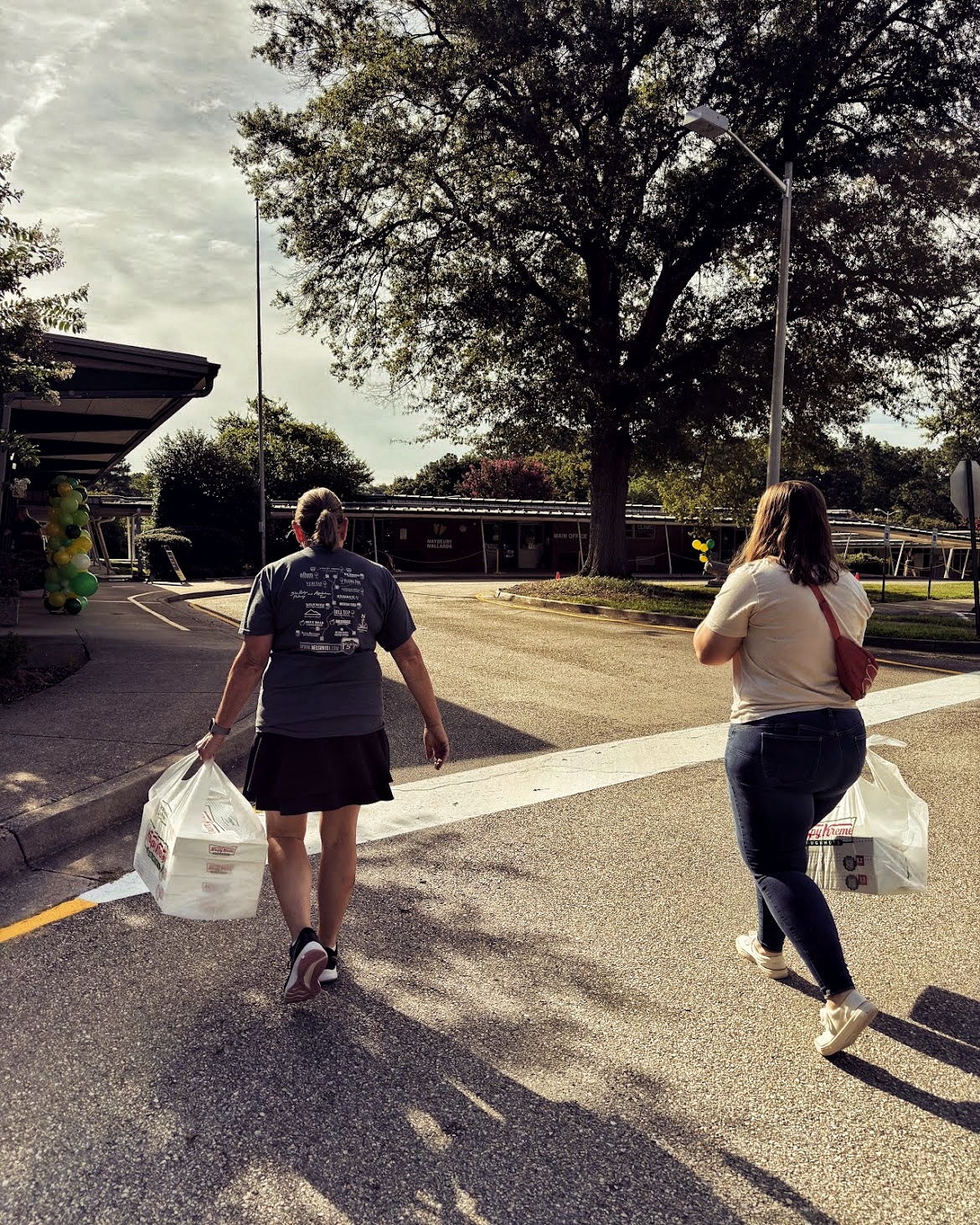 Two Welborne volunteers carrying donated goods toward a neighborhood school